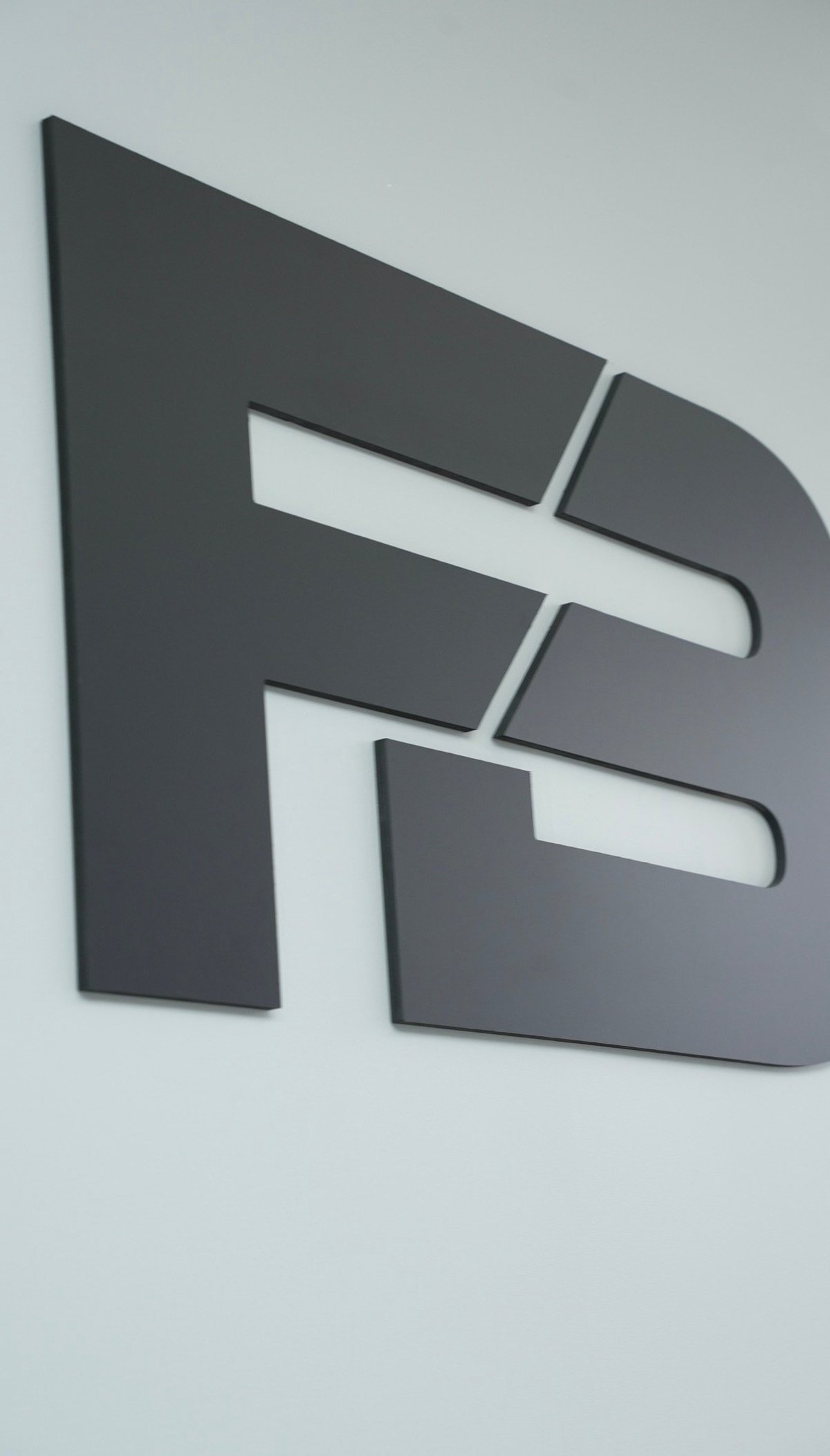Dark gray abstract letter E sign mounted on light gray wall with white rectangular cutouts